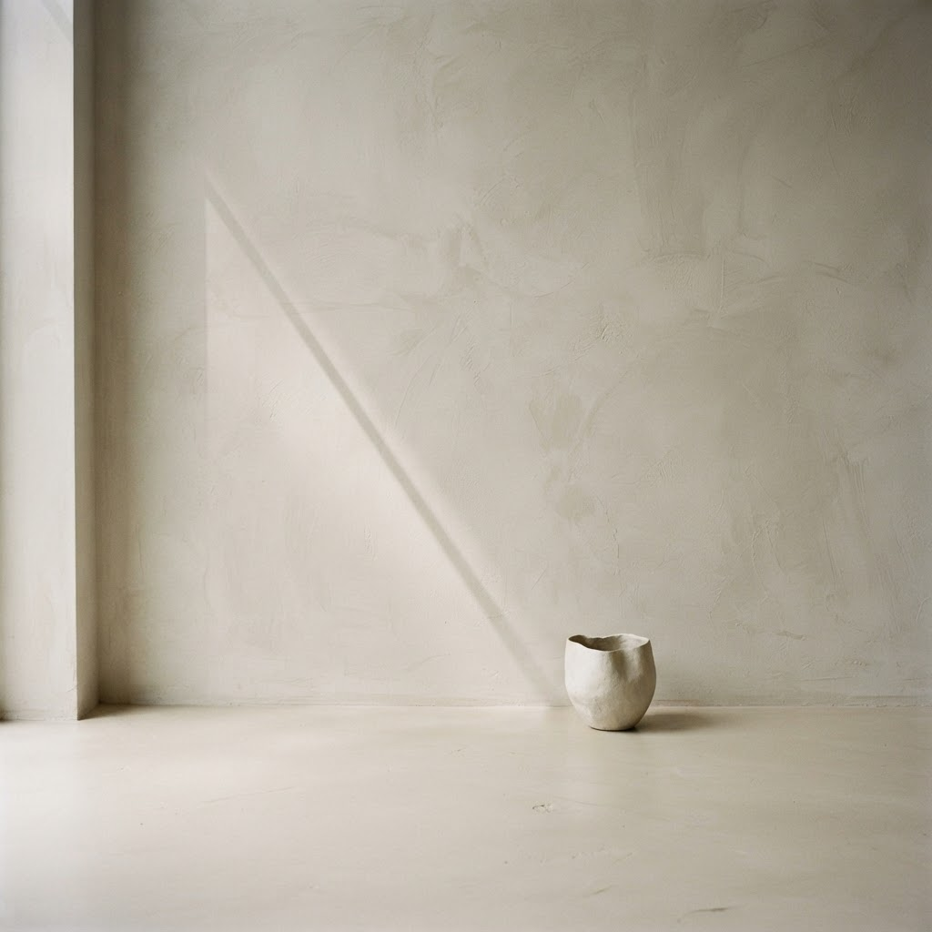 Soft, minimal microcement wall detail in warm neutral tones with a gentle diagonal shadow